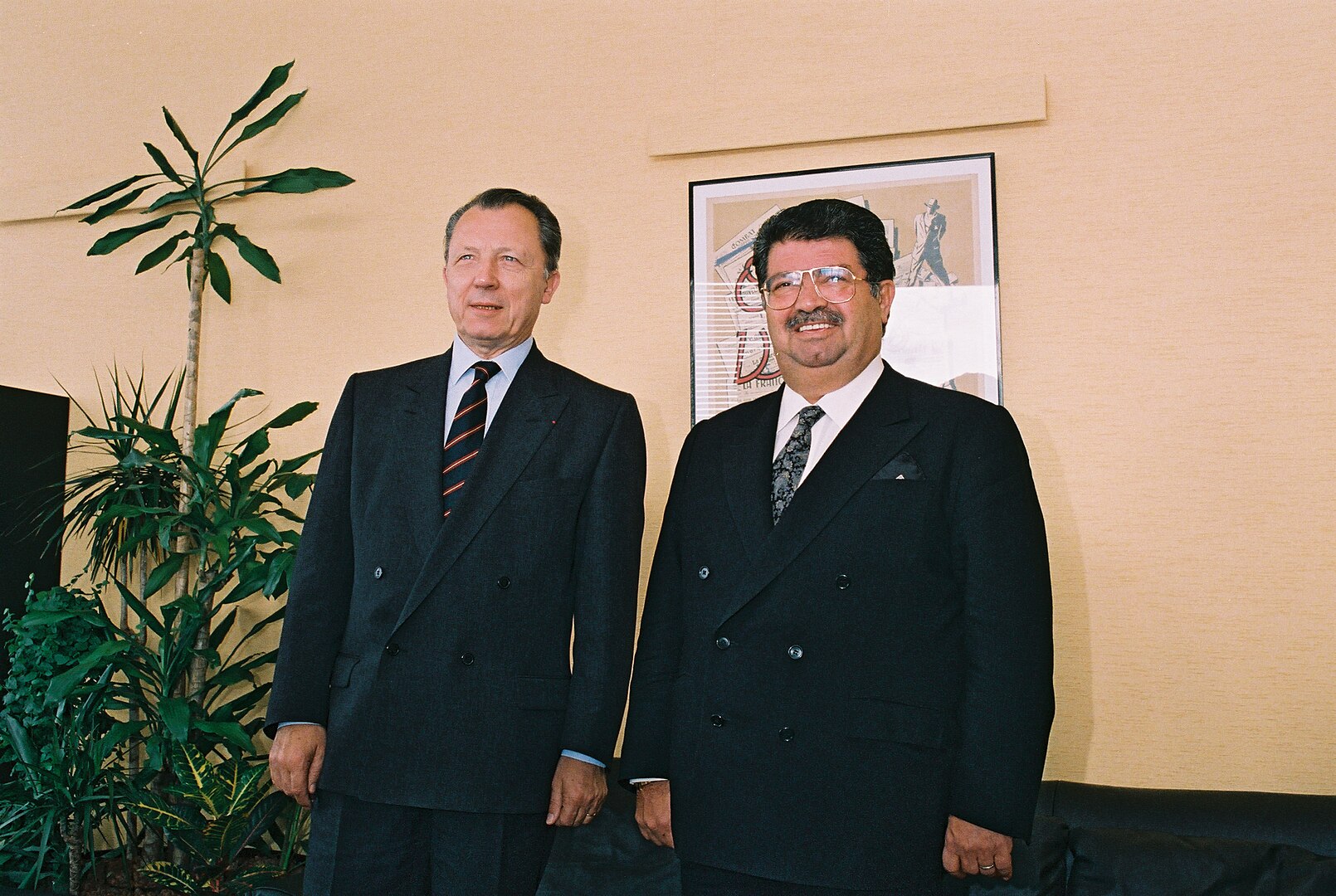 Zwei Männer in schwarzen Anzügen nebeneinander in einem Büro