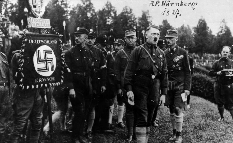Nürnberg Reichsparteitag 1927, Gruppenaufnahme, von rechts: Franz Pfeffer von Salomon [Franz von Pfeffer], Adolf Hitler, Gregor Strasser, Rudolf Hess, Heinrich Himmler, rechts SA-Standarte. Fotograf unbekannt, Quelle: Wikimedia Commons / Bundesarchiv Bild 146-1969-054-53A (CC-BY-SA 3.0).