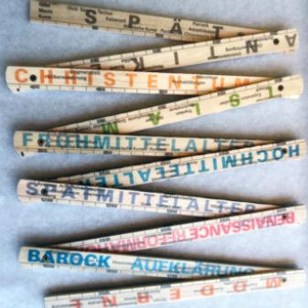 Ein Zollstock auf dem Begriffe stehen wie Christentum, Frühmittelalter, Barock etc.