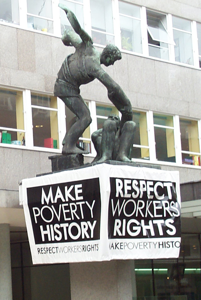 Skulptur mit Plakat „Make Poverty History“, Trades Union Congress, 5. Juli 2005, Great Britain. Fotograf: Kaihsu Tai ©, Quelle: Wikimedia Commons, Lizenz: CC BY-SA 3.0 Deed